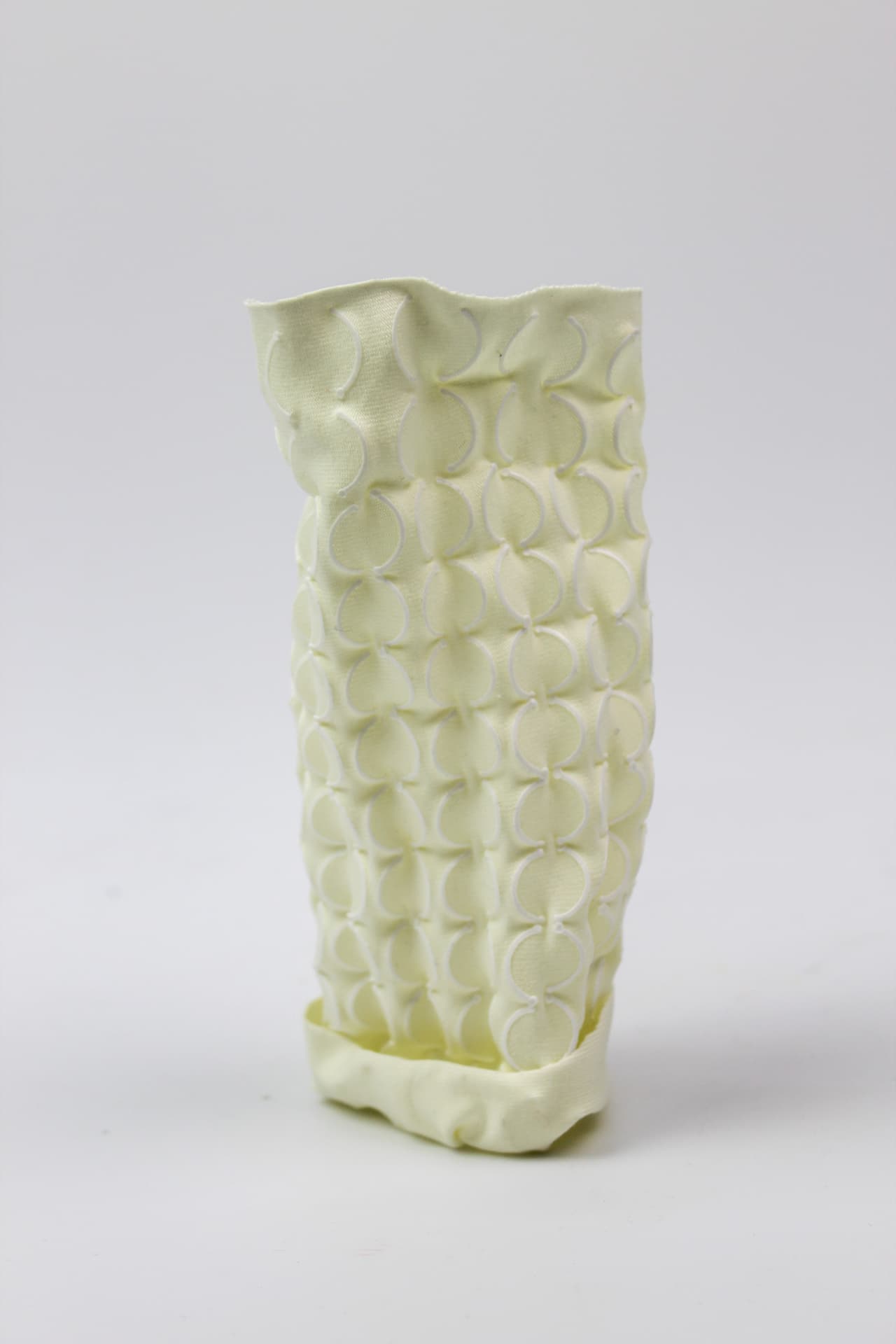 Cream textile vessel patterned with printed circular bosses.