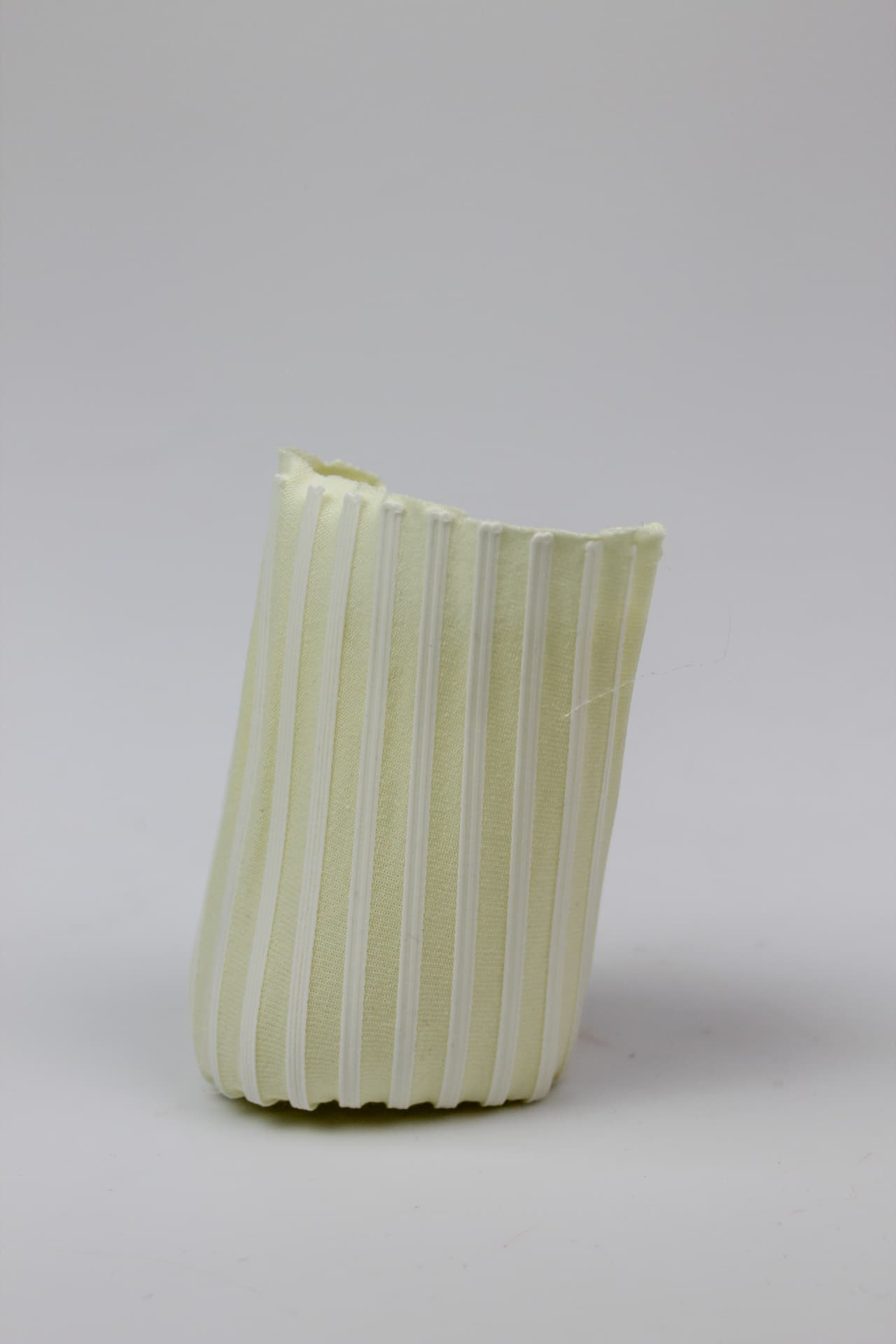 Pale pleated textile cylinder formed by vertical printed lines.