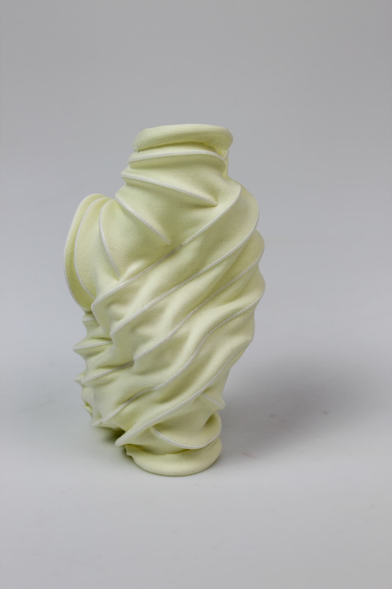 Cream textile form with a continuous spiralling printed seam.