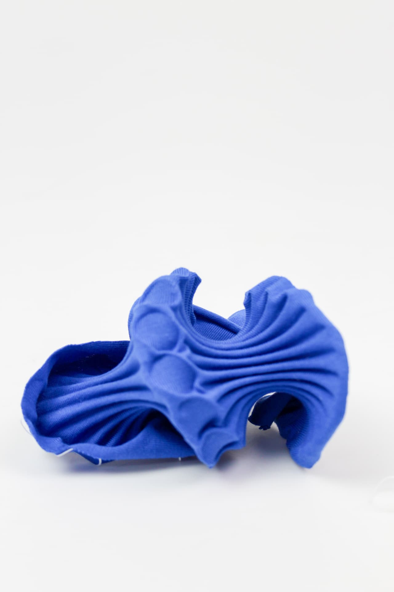 Blue 4D-printed textile shell with rippling folds and rounded bosses.