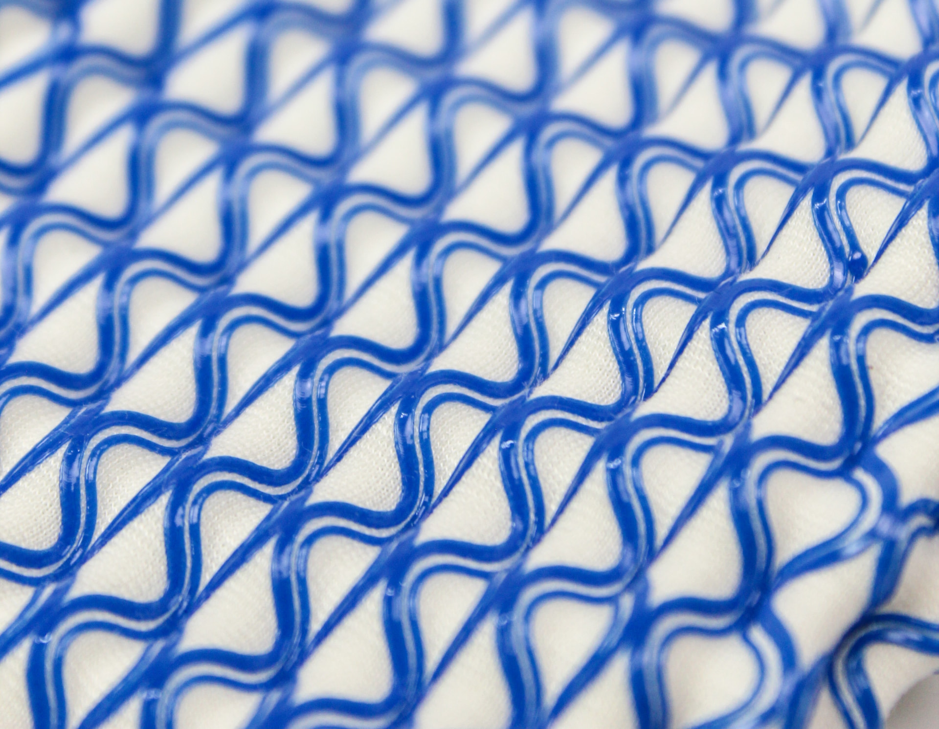 Close-up of a blue thermoplastic lattice printed onto white textile.