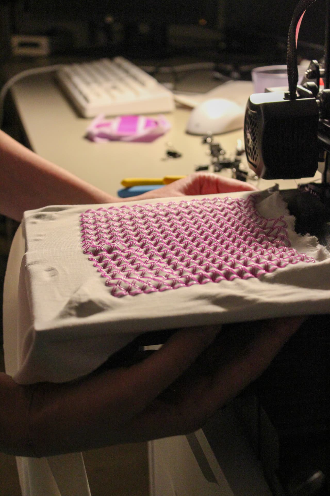 Pink thermoplastic lattice printed onto a white tensioned textile on the print bed.